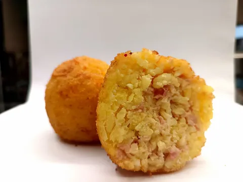 Arancino Cotto e Caciocavallo tagliato a metà, ripieno giallo zafferano con prosciutto cotto