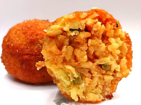 Arancino Ragù tagliato a metà, ripieno rosso con pomodoro e piselli