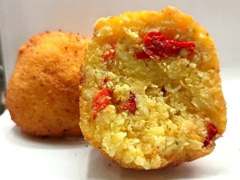 Arancino Baccalà e Peperoni tagliato a metà, ripieno giallo zafferano con peperoni rossi