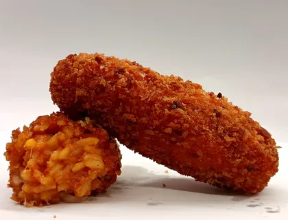 Supplì di riso tagliato a metà, ripieno rosso al pomodoro e carne